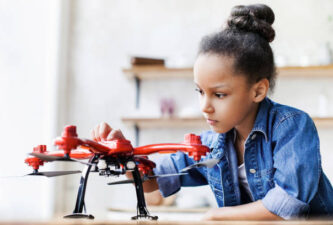 Young cute girl exploring drone quadcopter. Education, future, children, technology, science and modern people concept